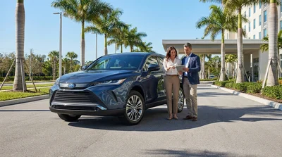 Silver car rental driving on a sunny highway surrounded by palm trees in Florida