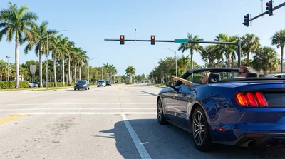 Car rental turning right at a red traffic light at a sunny Florida intersection