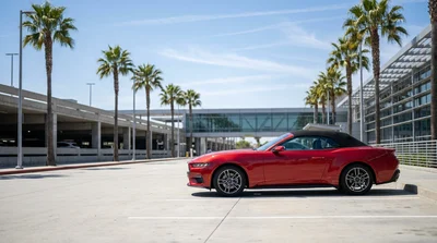 Red convertible car rental driving along a scenic coastal highway in California