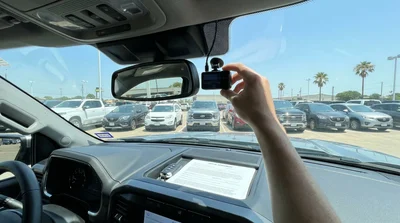 Small dash cam mounted on the interior windshield of a car rental driving along a sunny highway in Texas
