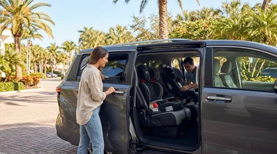 Parent buckling a toddler into a child seat inside a car hire in Florida with palm trees visible outside