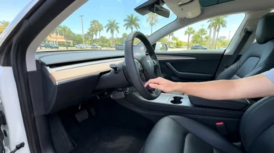 Driver using steering wheel hand controls in a car rental driving on a sunny road in Florida