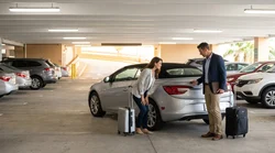 A person inspecting a white SUV at an Orlando airport car rental parking garage