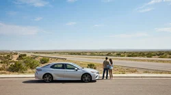 White SUV car rental driving on a straight desert highway in Texas under a clear sky