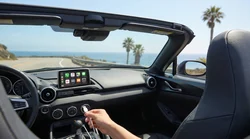 Smartphone connected via USB cable to an Apple CarPlay dashboard screen inside a California car rental