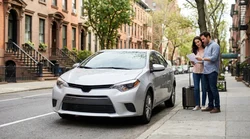 White car rental driving down a busy street in New York surrounded by yellow taxis