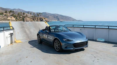 A white car rental parked on a ferry deck crossing a bay in California