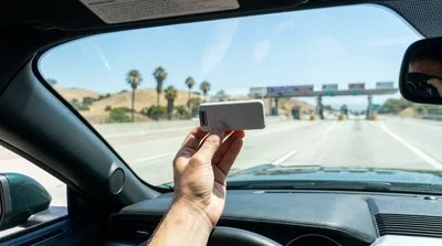 Dashboard view from a car rental driving on a sunny California highway towards a toll plaza