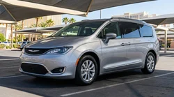 White car rental driving past colorful neon signs and tall resorts in Las Vegas