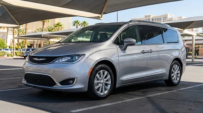 White car rental driving past colorful neon signs and tall resorts in Las Vegas