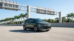 Red car rental driving under an electronic toll gantry on a sunny Florida highway