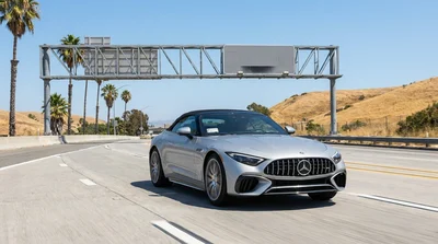 Person driving a car rental on a sunny California highway passing under a toll sign