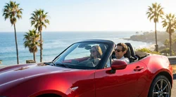 Red convertible car rental driving down a sunny palm tree lined street in Los Angeles
