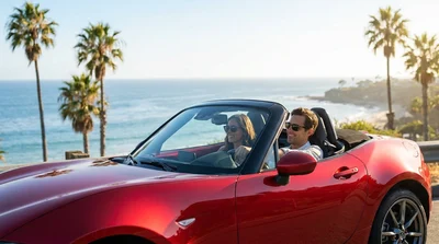 Red convertible car rental driving down a sunny palm tree lined street in Los Angeles