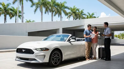 White convertible car hire parked under green palm trees on a sunny street in Miami