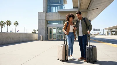 Traveler with a suitcase waiting at a car rental shuttle stop outside Union Station in Los Angeles