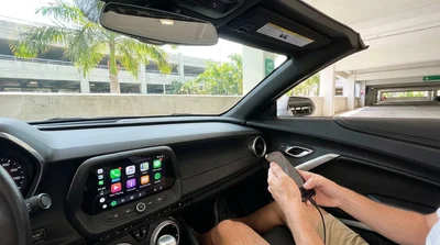 Driver connecting a smartphone to the dashboard screen of a car rental in Miami