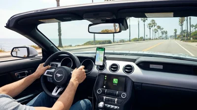 Smartphone secured in a hands-free dashboard mount inside a car rental on a sunny California highway