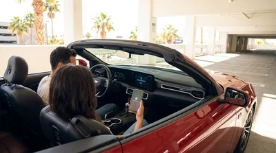 Driver setting up Apple CarPlay on a car rental dashboard with the Las Vegas Strip visible through the windshield