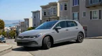 White compact car rental parked on a steep San Francisco street with city views
