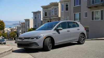 White compact car rental parked on a steep San Francisco street with city views