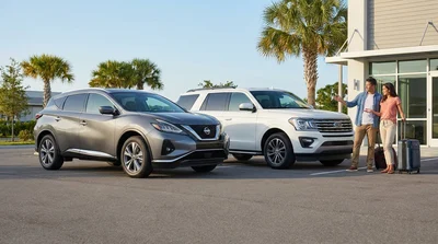 White standard and intermediate SUV car hire vehicles parked under palm trees on a sunny Florida road