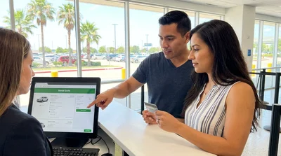 A man reviewing a car rental contract on a tablet while leaning against a white SUV in Texas