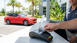 A person handing a credit card to a staff member at a car hire desk in Orlando