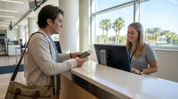 Customer handing a driver's license to an agent at a car rental desk in Orlando
