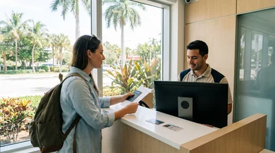 Customer presenting paperwork to a clerk at a car rental desk in Miami