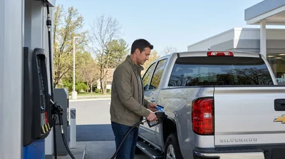 Person filling the gas tank of a white car hire at a fuel station in Pennsylvania