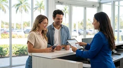 A person signing paperwork at a Florida car hire desk with keys on the counter