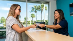 Customer handing a credit card to a clerk at a car hire desk in Orlando