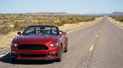 Silver car rental driving down a long open asphalt highway in the Texas desert