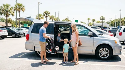Family loading suitcases into the trunk of a car rental under palm trees in Florida