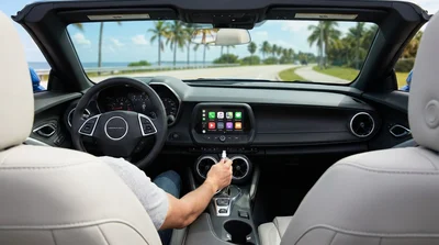 Apple CarPlay display on a car rental dashboard with sunny Florida palm trees seen through the windshield