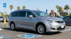 Silver car rental parked in a blue accessible parking space in California with a painted white wheelchair symbol