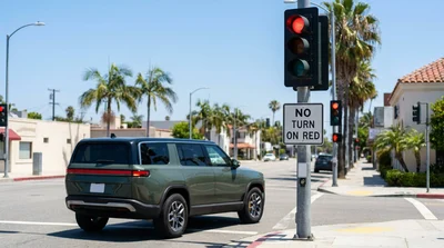 White car hire stopped at a red traffic light at a sunny street intersection in California