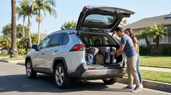 Suitcases loaded into the open trunk of an intermediate SUV car rental parked on a sunny street in Los Angeles