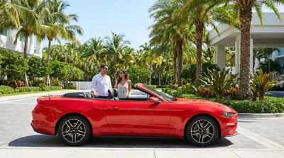 White car hire driving along a sunny coastal highway surrounded by palm trees in Florida