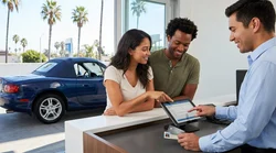 Two friends picking up a car rental at an outdoor parking lot in Los Angeles