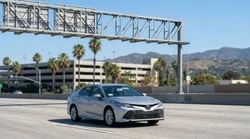 Driver in a white car rental passing an ExpressLanes toll sign on a Los Angeles highway