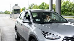 Silver car rental driving through an E-ZPass toll plaza on a Pennsylvania highway