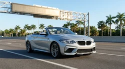 White car rental passing through an electronic toll booth on a sunny Florida highway