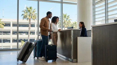 Traveler with luggage checking in at a Los Angeles airport car rental desk