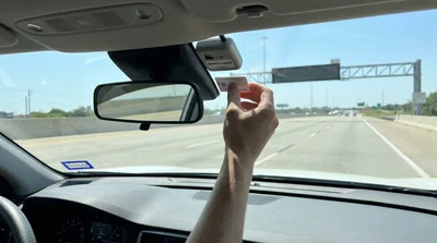 Electronic toll tag on the windshield of a car rental driving on a Texas highway