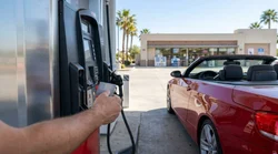 Close-up of a person using a credit card at a California gas station pump to refuel a car rental