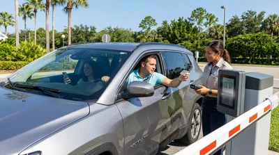 A car hire is stopped at a theme park parking entrance gate in Orlando with the barrier arm down