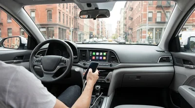 Hand touching an Apple CarPlay screen on the dashboard of a car rental parked on a New York street