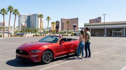 A customer receiving vehicle keys from an agent at a car rental desk in Las Vegas